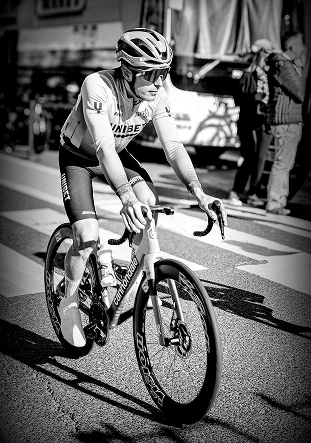 Photo en noir et blanc d'un cycliste professionnel sur un vélo de route, faisant preuve de concentration et de détermination pendant une course.